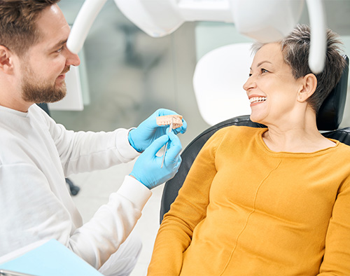 Dentist showing smiling patient model of teeth