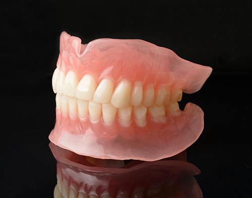 Full set of dentures on reflective black surface