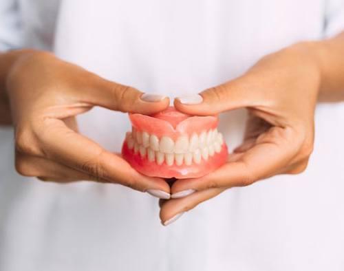 Lady presents viewer with dentures
