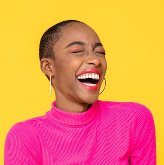 Woman smiling and laughing on a bright yellow background