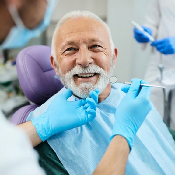 Man smiling while dentist examines his teeth