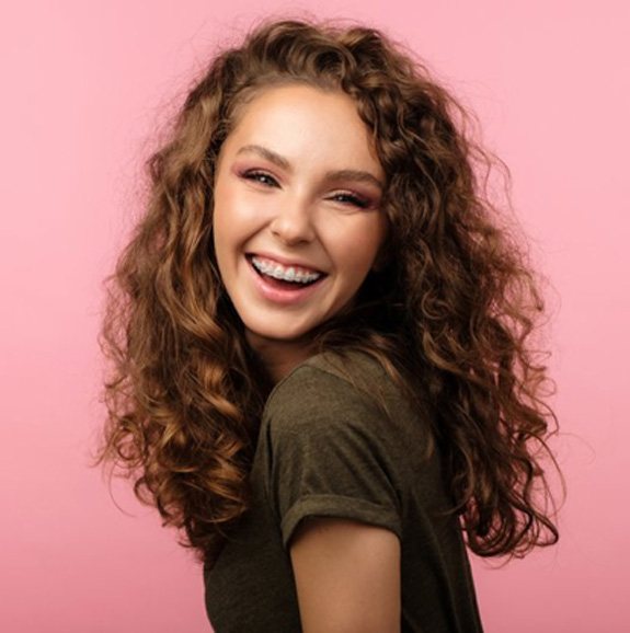 Woman with braces smiling on pink background