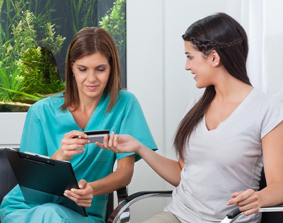 A woman using a credit card to pay for dental treatment