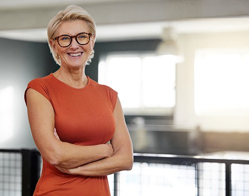 Senior woman in orange shirt smiling with arms folded