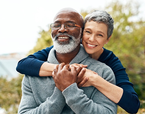 Senior man being hugged from behind by senior woman