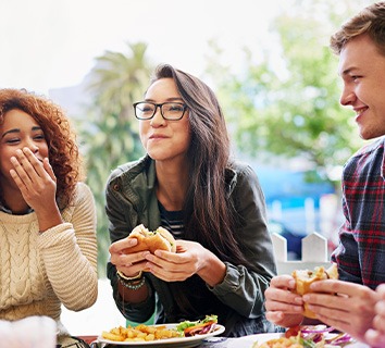 Group of friends smiling while eating lunch together