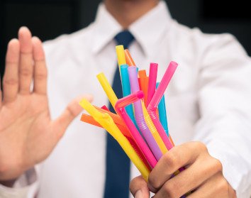 One hand saying “no” to another hand full of colorful plastic straws